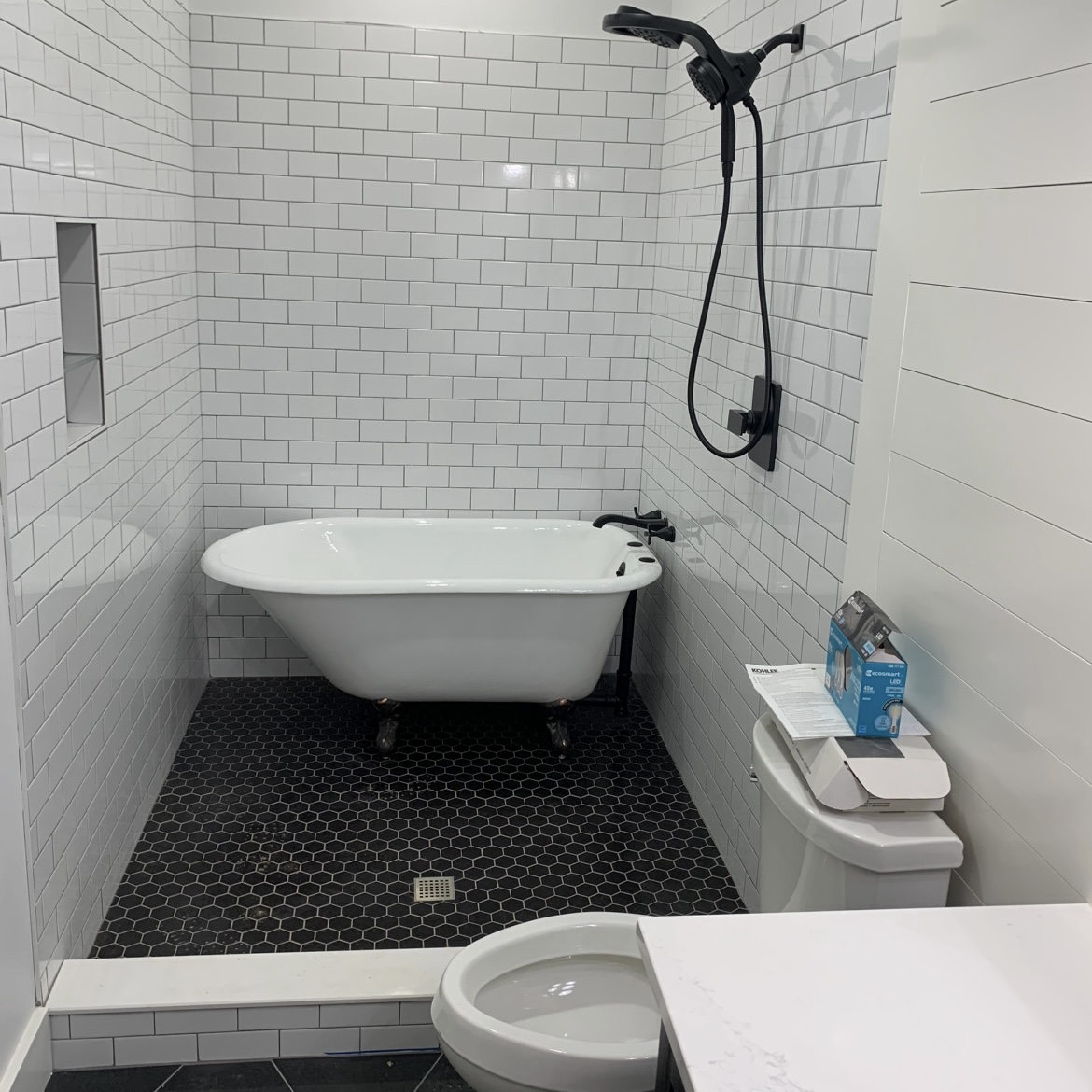 Freestanding tub and shower in black-and-white tile bathroom